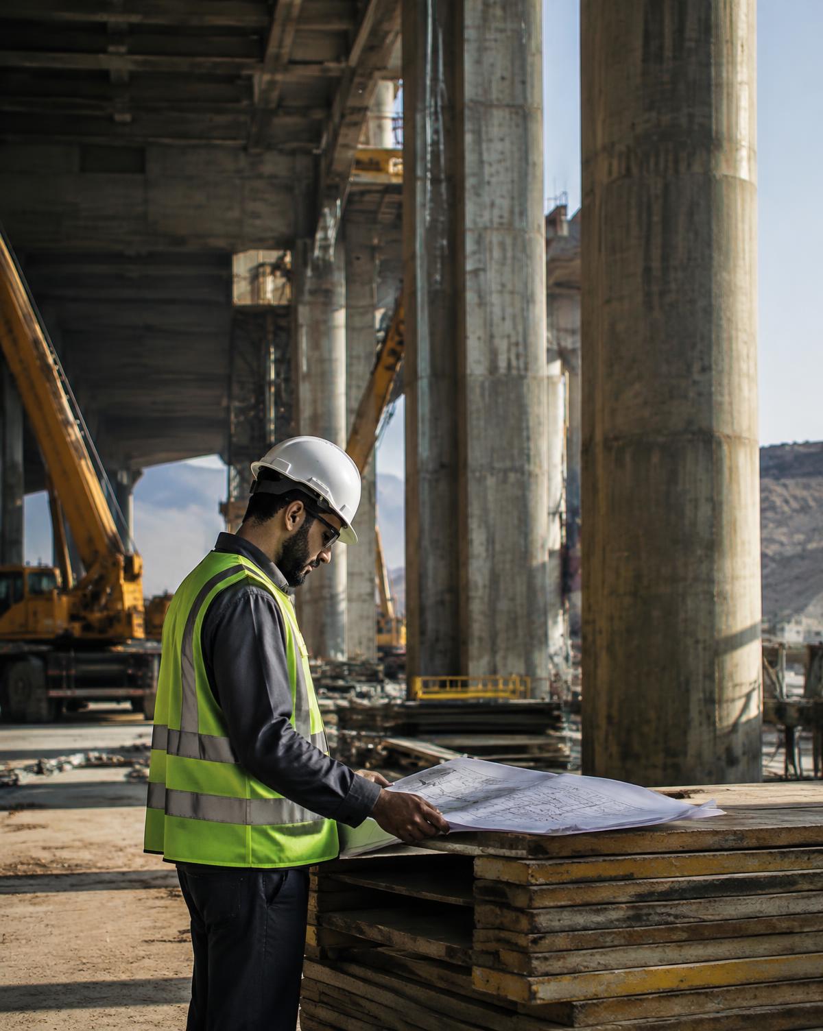 Construction professional reviewing plans at an active site